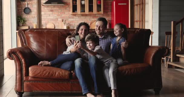 Famille avec enfants assis sur le canapé s'amuser en utilisant un smartphone — Video