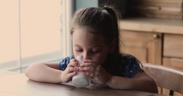 Niña sentada en la mesa bebiendo leche bebida — Vídeo de stock