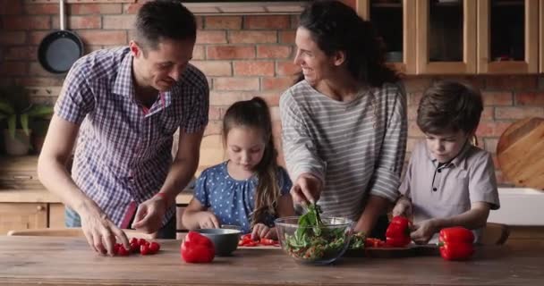Женатая пара учит детей готовить на домашней кухне — стоковое видео