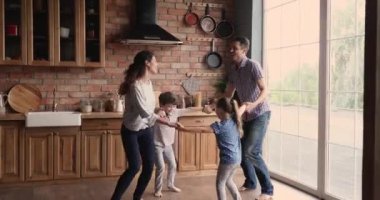 Çocuklar el ele tutuşup modern mutfakta dans ediyorlar.