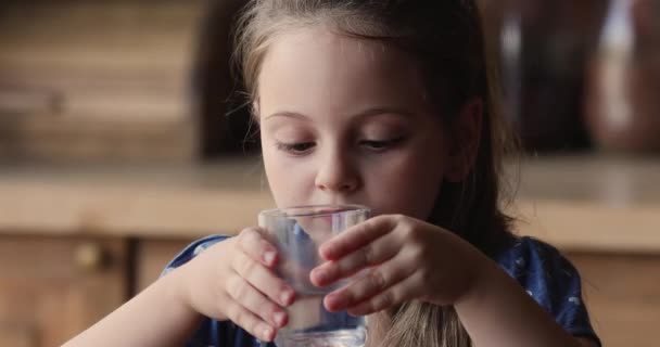 Yakından bakınca, cam tutan küçük kız doğal su içiyor. — Stok video