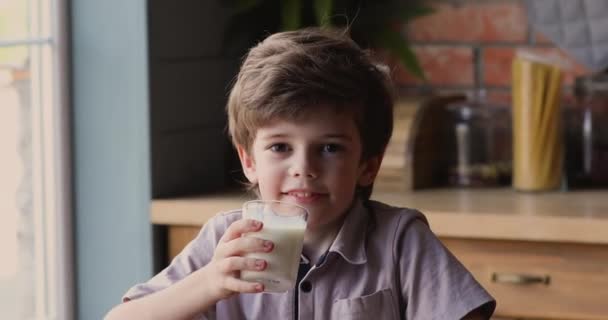 Malý chlapec sedí v kuchyni a drží sklenici mléka — Stock video