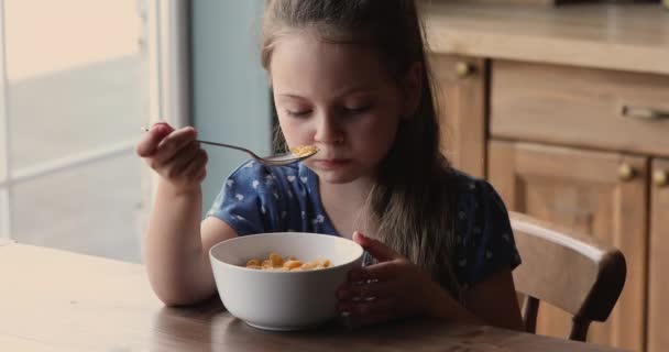 Little girl sitting at dining table eating cornflakes with milk — Stock Video