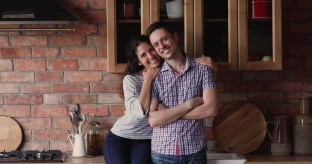 Felice coppia che si abbraccia in cucina sorridente guardando la fotocamera — Video Stock
