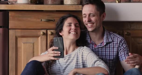 Пара сидящих на кухне со смартфоном, смотрящих смешные видео — стоковое видео