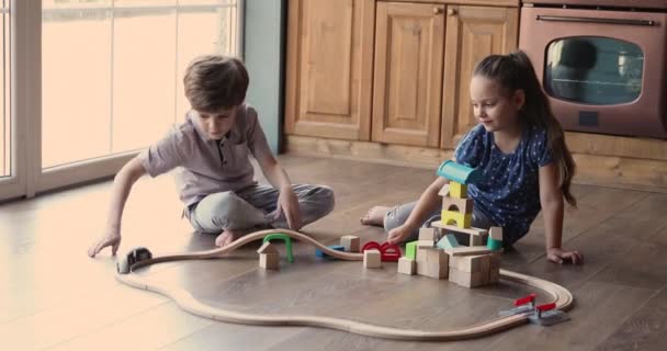 Kız ve erkek evde oyuncak demiryolu oynuyorlar. — Stok video