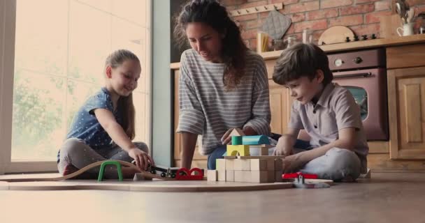 Moeder met kinderen spelen houten blokken en speelgoed spoorweg — Stockvideo