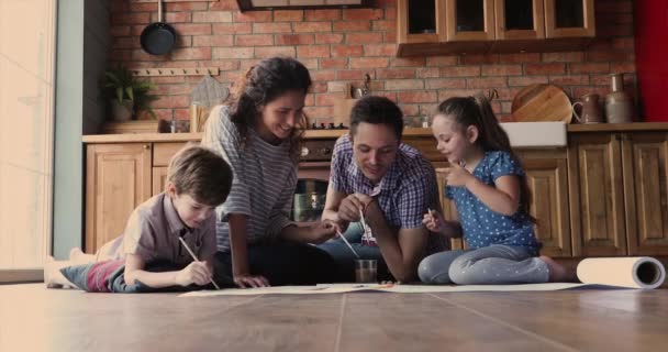 Родители и их дети рисуют красками, сидя на полу — стоковое видео