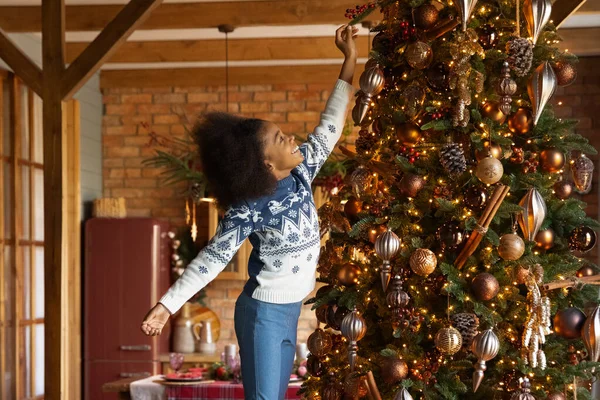 Extasiado menina afro-americana decorando árvore de Natal em casa — Fotografia de Stock