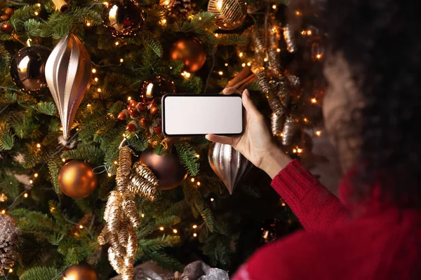 Africano americano mulher segurando telefone com tela branca, celebrando o Natal — Fotografia de Stock