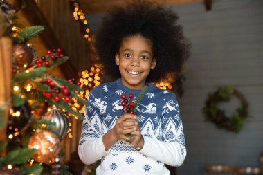 Noel hediyesi taşıyan gülümseyen Afrikalı Amerikalı bir kızın portresi.