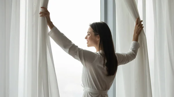 Successful young woman buyer of apartment standing by large window