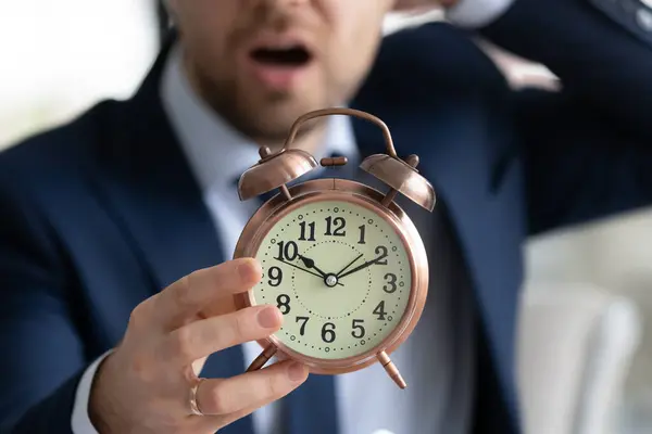 Zamartwiany młody mężczyzna menedżer pracownik w formalnym nosić trzyma zegar. — Zdjęcie stockowe