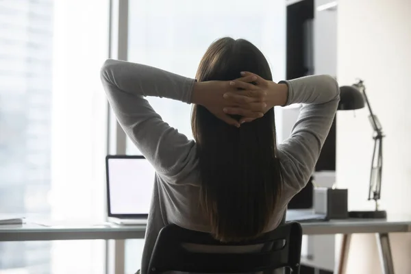 Achteraanzicht van vrouwelijke werknemer ontspannen met handen over het hoofd — Stockfoto