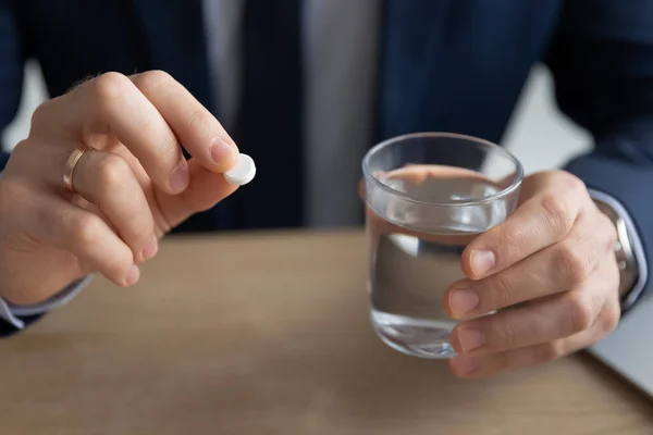 Close up young businessman thinking of taking painkiller. — Stock Photo, Image