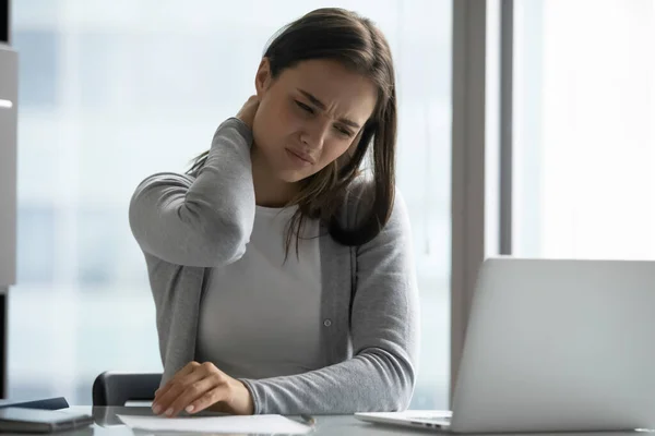 Niezdrowa młoda kobieta siedzi w miejscu pracy tarcie szyi uczucie bólu — Zdjęcie stockowe