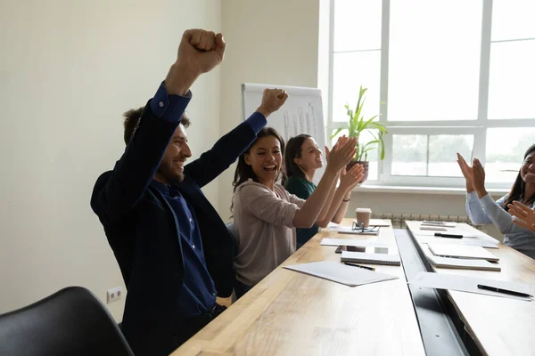 Overjoyed diverse team clapping hands congratulating happy coworker with promotion