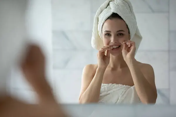 Agréable dame de nettoyage des dents avec fil dentaire après la douche du matin — Photo