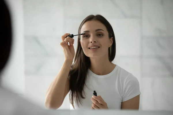 Inspirierte Millennial-Frau macht sich Mascara auf die Wimpern — Stockfoto