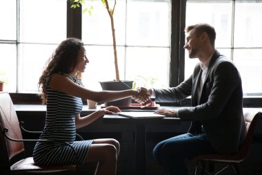 Kafedeki erkek danışmanla el sıkışmaktan memnun olan zenci kadın müvekkil.