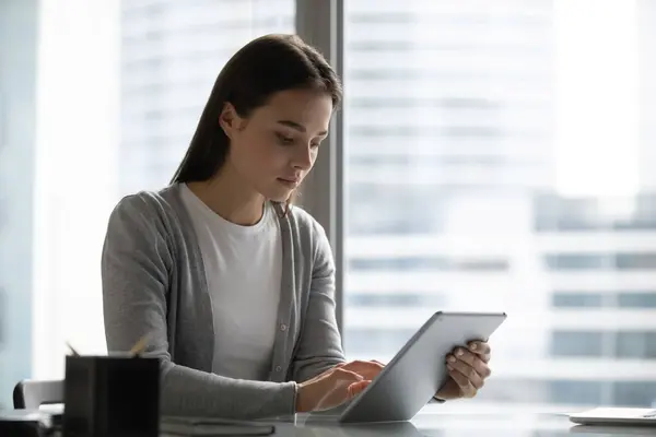 Millennial gerente femenino sentado en el escritorio de trabajo en la tableta de PC — Foto de Stock