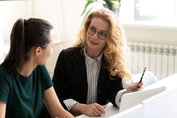 Friendly capable mature businesswoman training younger colleague intern — Stock Photo, Image