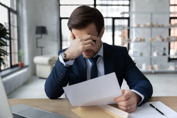 Förvirrad ung affärsman känner sig stressad över dåliga nyheter i brev. — Stockfoto