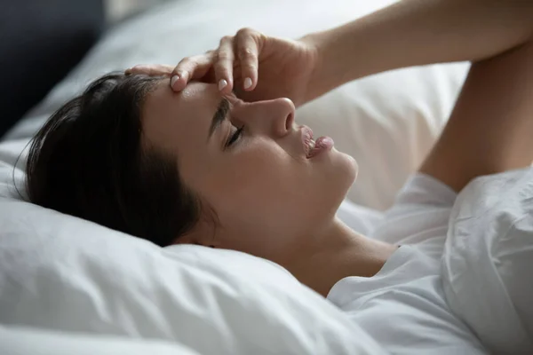 Triest wijfje liggend in kussens die het voorhoofd raken en lijden aan migraine — Stockfoto