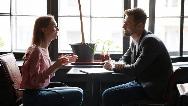 Diversos parceiros milenares discutindo detalhes de inicialização à mesa no café — Fotografia de Stock