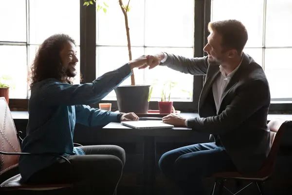 Dos diversos amigos hombres golpeando puños por encima de la mesa en el café — Foto de Stock