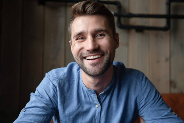 Headshot of smiling millennial man talking with friends online