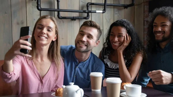 Glædelig forskelligartede hjælpere selskab poserer for gruppe selfie på cafe - Stock-foto