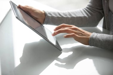 İnternette tablet üzerinde çalışan genç bir kadının elleri