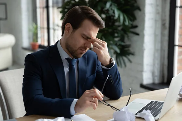 Infeliz joven hombre de negocios cansado en traje formal quitándose las gafas. — Foto de Stock