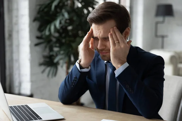 Ongezonde duizendjarige zakenman in formele dragen masserende tempels. — Stockfoto