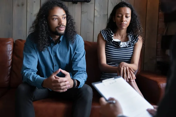 Young anxious biracial family couple having consultation at therapist office