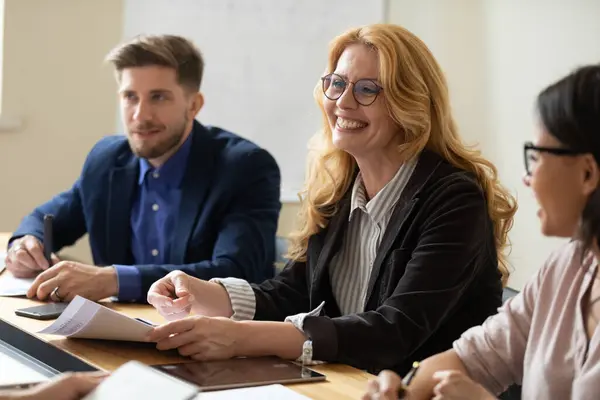 Experienced senior female coach teaching diverse interns at conference table — Stock Photo, Image