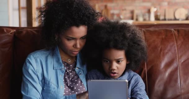 Mãe africana educar pequena filha segurando tablet usando o site da internet — Vídeo de Stock
