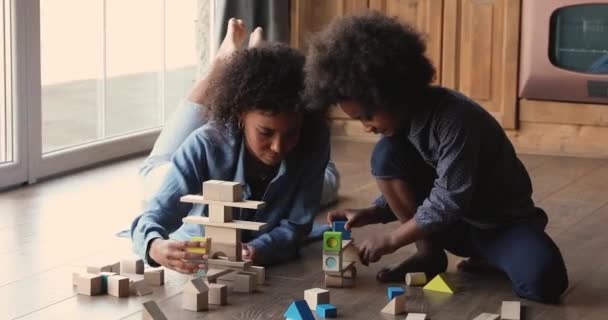 Afrikalı anne. Küçük anaokulu kızı içeride tahta bloklar oynuyor. — Stok video