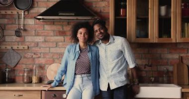 Afrikalı çift mutfakta kameraya bakıp gülümsüyor.