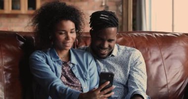 Afrikalı çift akıllı telefon cihazıyla koltukta dinleniyor.