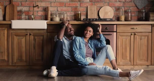 Pareja africana sentarse en el suelo riendo relajarse en la cocina — Vídeo de stock