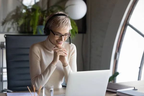 Glimlachende zakenvrouw draagt headset consulting client online in kantoor — Stockfoto