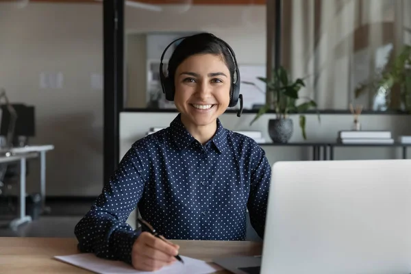 Head shot portrait smiling Indian woman wearing headphones studying online