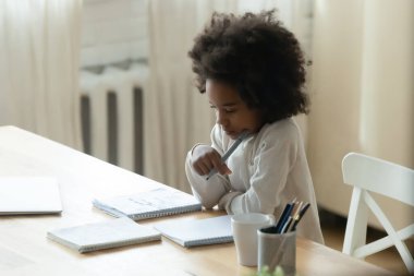 Düşünceli Afrikalı Amerikalı küçük kız evde ders çalışıyor.