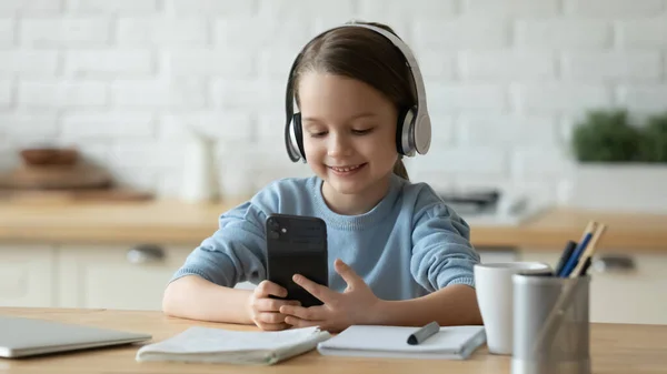 Glimlachend meisje met een koptelefoon, afgeleid van het studeren. — Stockfoto