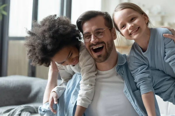 Щасливий батько з двома доньками розважається, граючи смішну гру — стокове фото