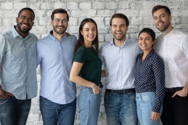 Mutlu genç insanlar takım arkadaşları kucaklaşıp kameraya bakıyor.