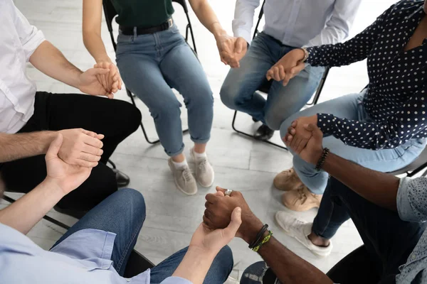 Diverse people group sitting on chairs in circle uniting hands