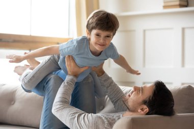 Baba kucağında küçük bir çocuk, uçuyormuş gibi yapıyor, komik oyunlar oynuyor.